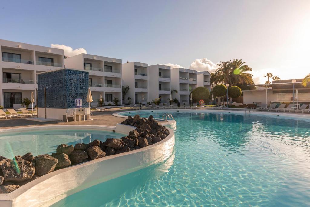 a swimming pool with rocks in front of a hotel at Oasis Lanz Beach Mate in Costa Teguise