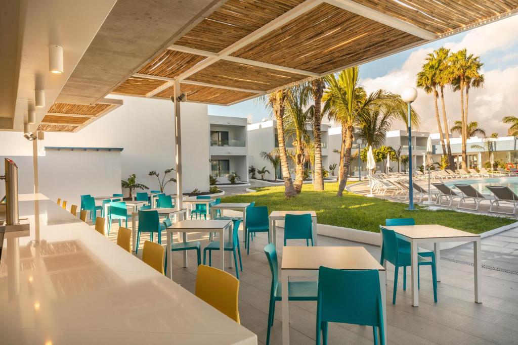 a restaurant with tables and chairs and palm trees at Oasis Lanz Beach Mate in Costa Teguise