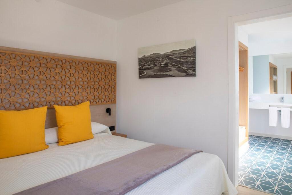 a bedroom with a large bed with yellow pillows at Oasis Lanz Beach Mate in Costa Teguise