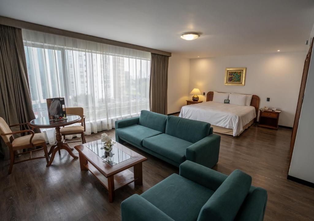 a hotel room with a bed and a couch and a living room at LUOXO Hotel in Lima