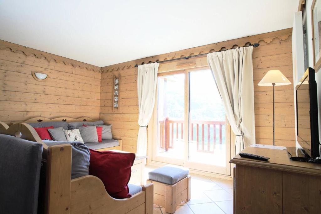 un salon avec un canapé et une grande fenêtre dans l'établissement Les Chalets Du Gypse - LES CHALETS DU GYPSE C05 MAE-3611, à Saint-Martin-de-Belleville