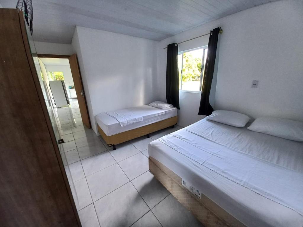 a bedroom with two beds and a bathroom with a mirror at Guesthouse da Barra in Florianópolis