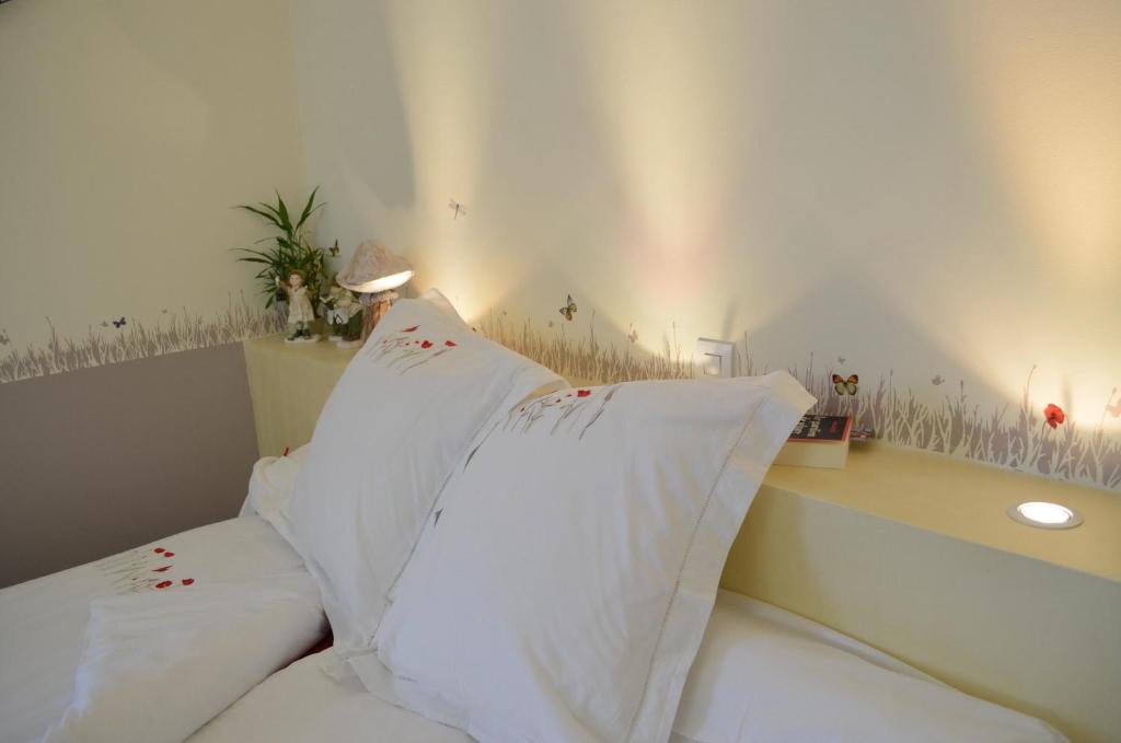 um quarto com almofadas brancas numa cama com uma secretária em Couette Et Cafe Crème em Le Coudray