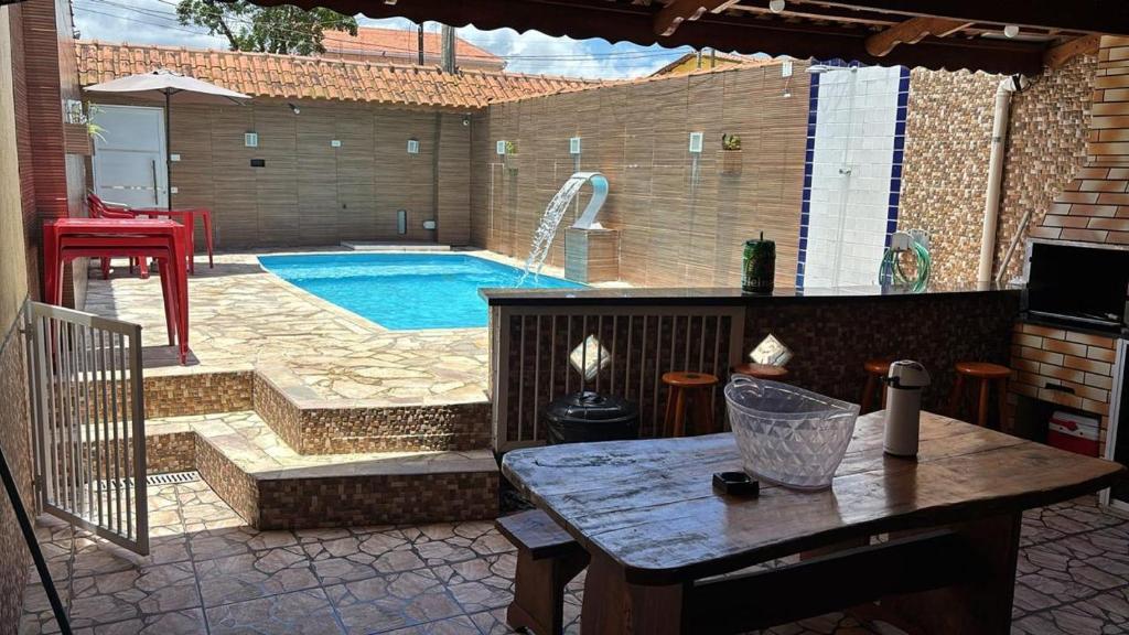 a patio with a swimming pool and a table with a table at Piscina, Churrasqueira, Ar Condicionado e 3 Vagas de Garagem in Mongaguá