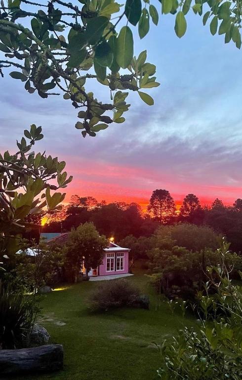 a house in a yard with a sunset in the background at Reserva Pedra da Mata in Pelotas