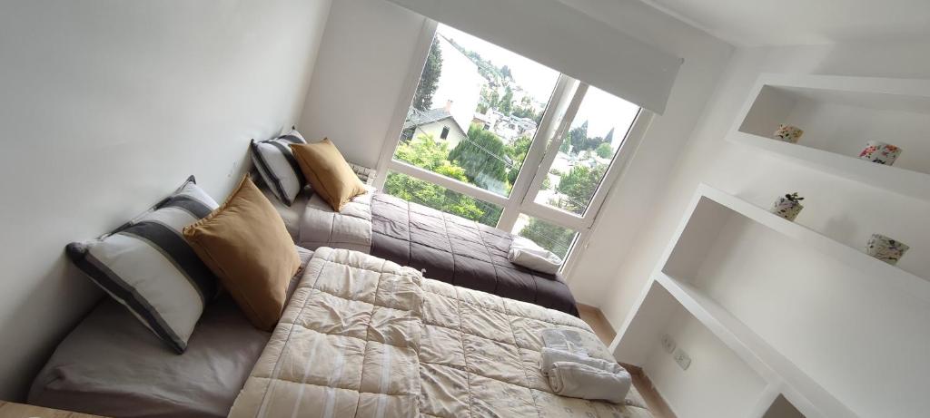 Un dormitorio con una cama y una ventana grande en Loft céntrico y moderno con vista al lago, en San Carlos de Bariloche