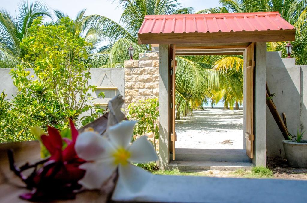 a door to a yard with flowers in the foreground at Cerulean View Residence in Hanimaadhoo