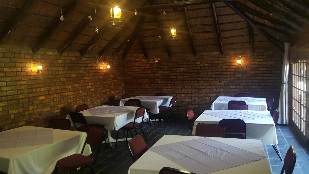 a room with white tables and chairs and a brick wall at Albatross B&B in Benoni