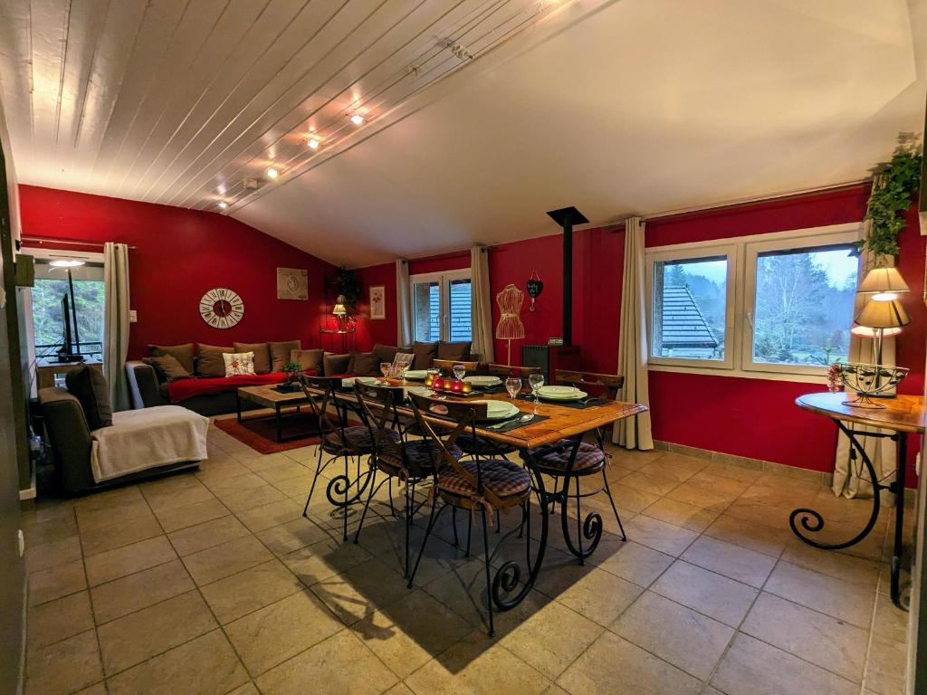 a living room with red walls and a table and chairs at Gîte calme avec jardin zen, piscine et randonnée au Parc des Vosges - FR-1-589-763 in Cornimont