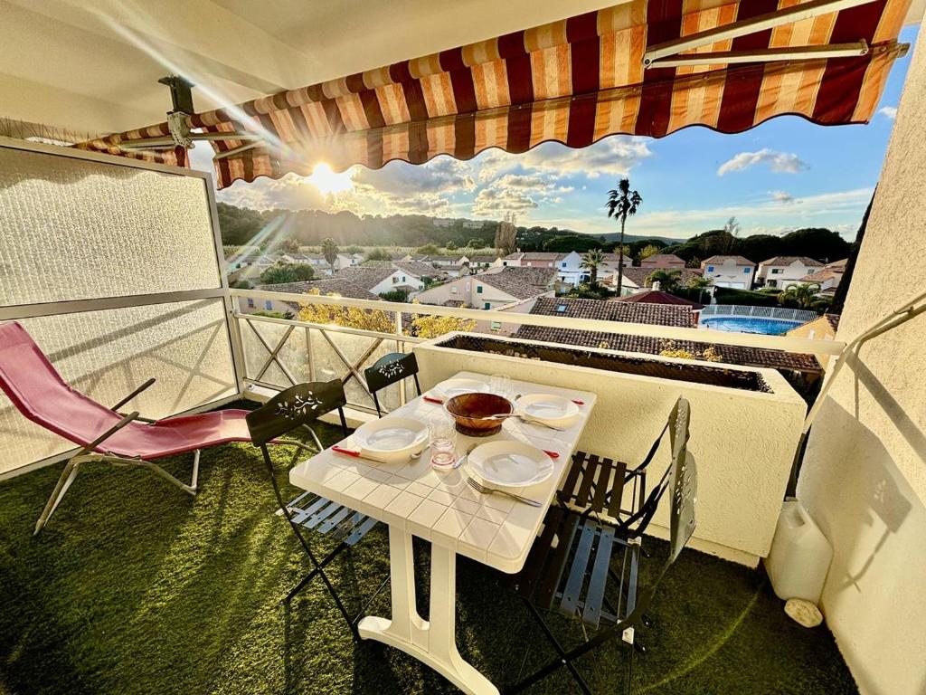 une table et des chaises sur un balcon avec vue dans l'établissement T2 Climatisé Proche Plage avec Terrasse et Garage - FR-1-816-14, au Lavandou