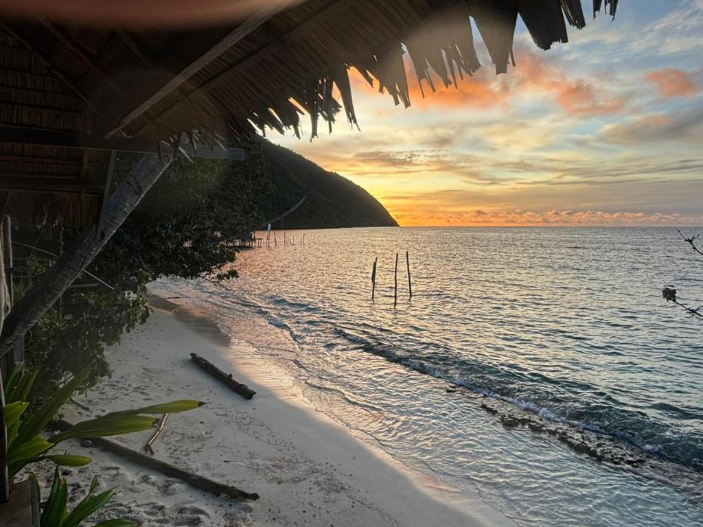 a view of a beach with a sunset in the background at Moana Raja Ampat Homestay in Poelau Mansoear