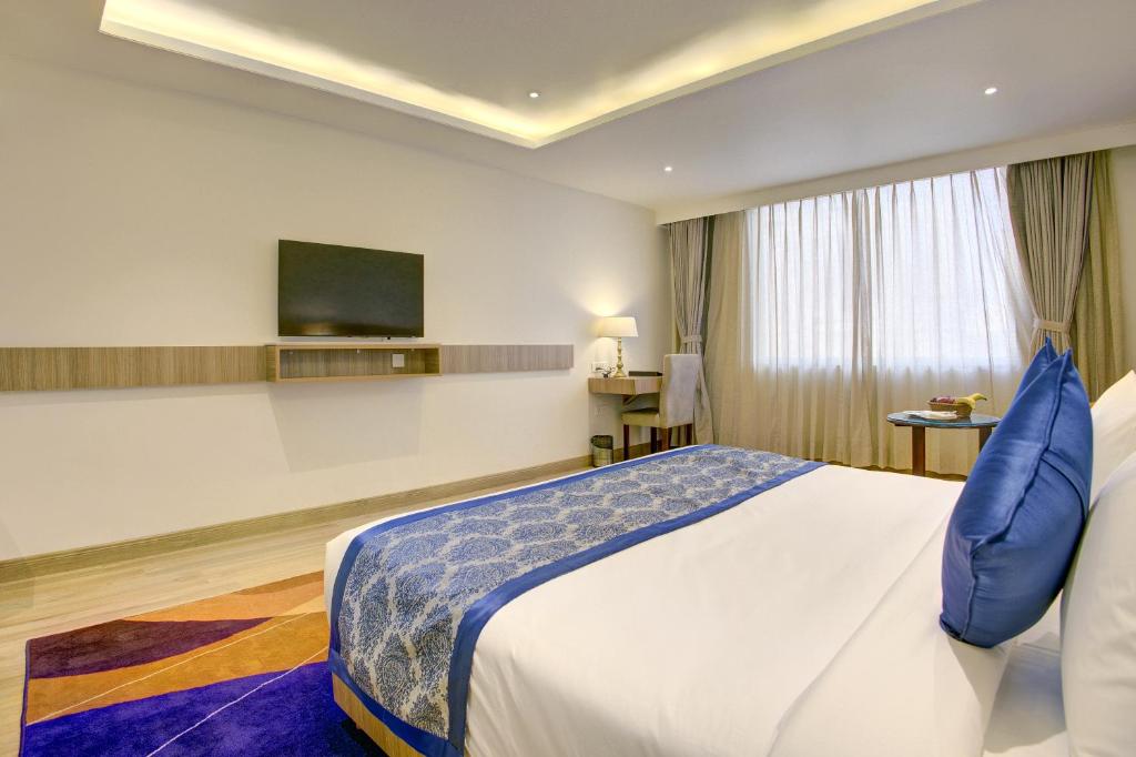 a hotel room with a bed and a flat screen tv at Cygnett Inn Airport in Mohāna