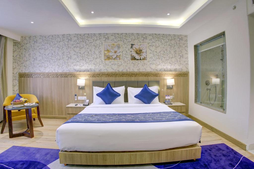 a bedroom with a large bed with blue pillows at Cygnett Inn Airport in Mohāna