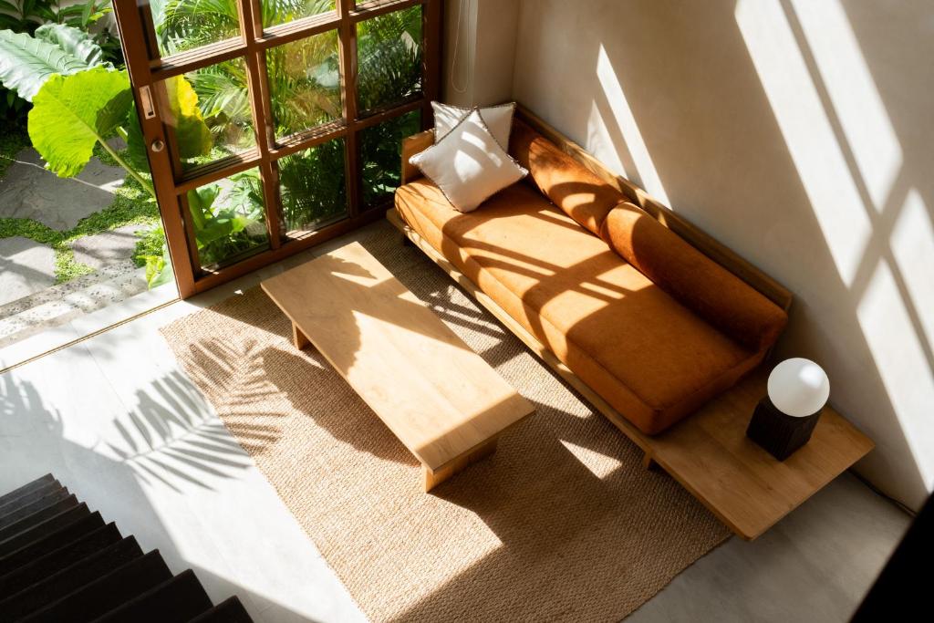 ein Wohnzimmer mit einer Couch vor einem Fenster in der Unterkunft Calista Studios SATU Tasteful 1 BR home in peaceful jungle, 10 mins away from the buzz of Uluwatu in Uluwatu