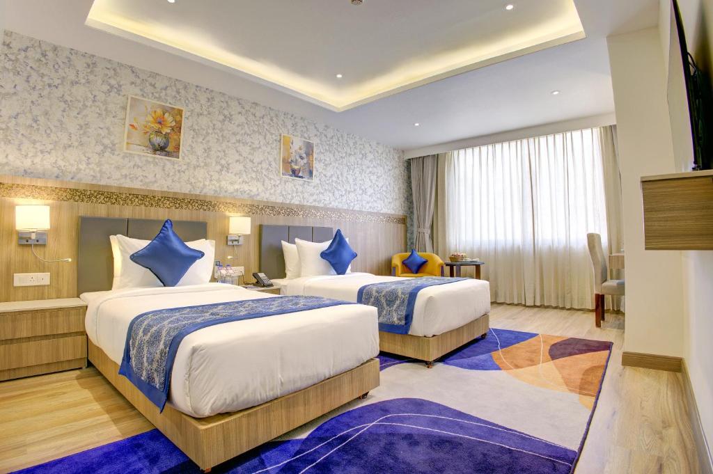 a hotel room with two beds with blue sheets at Cygnett Inn Airport in Mohāna