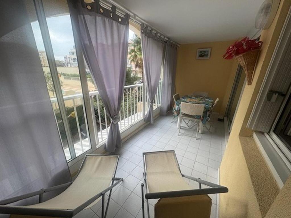 - deux chaises et une table dans une chambre avec fenêtre dans l'établissement Appartement T2 Cabine, piscine, parking, près plage Cap d'Agde - FR-1-749-76, au Cap d'Agde