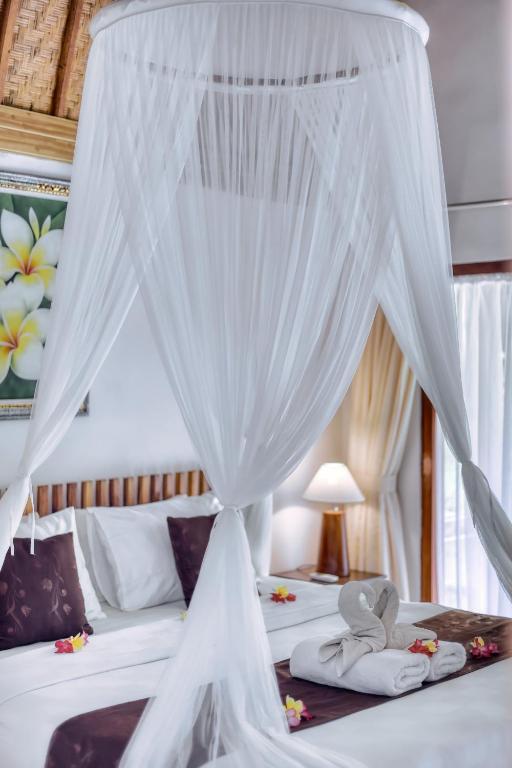 a bedroom with two beds with white mosquito nets at Komurd Lavender Bungalow in Nusa Penida