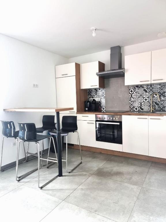 une cuisine avec des armoires blanches et une table et des chaises dans l'établissement Start appart, à Village-Neuf