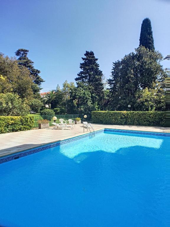 une grande piscine bleue avec des chaises et des arbres dans l'établissement Superbe studio jardin, terrasse, piscine 307L Kali, à Cannes