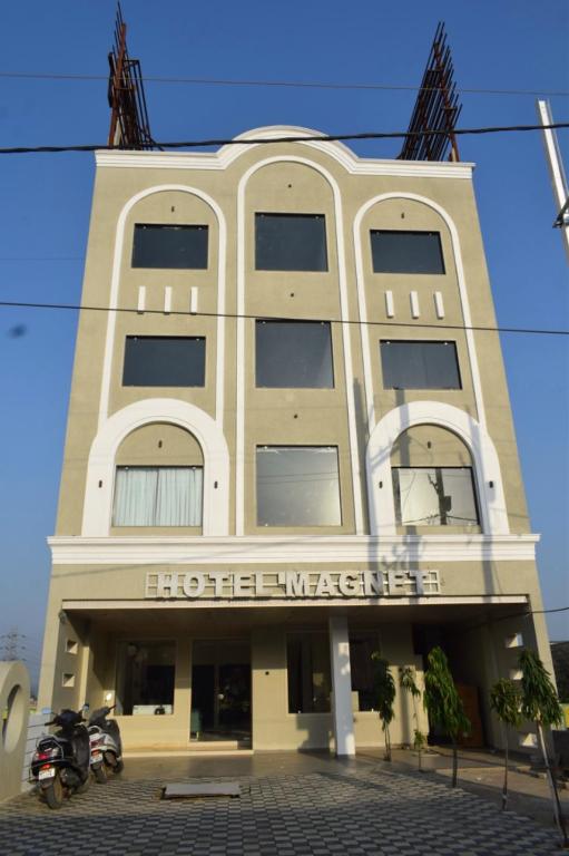 a building with a motorcycle parked in front of it at Hotel Magnet in Indore