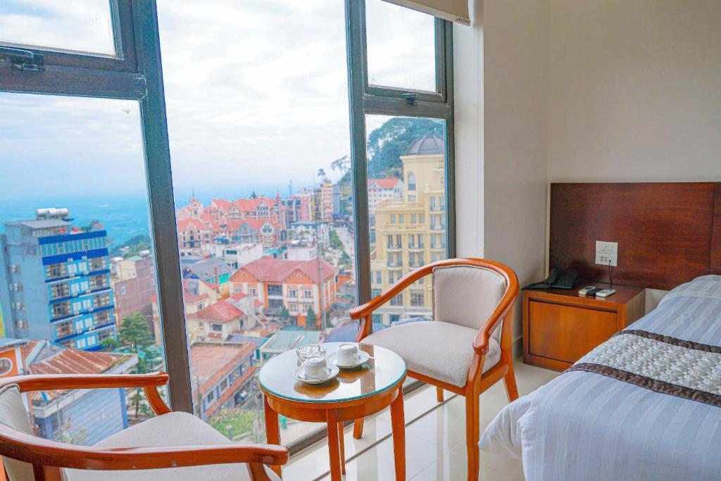 a room with a bed and two chairs and a window at Ngan Ha Hotel Tam Dao Panorama View in Tam Ðảo