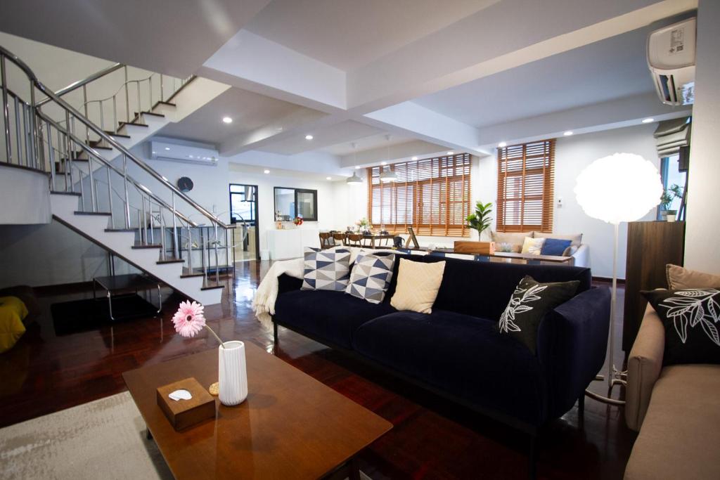 a living room with a blue couch and a staircase at Spacious 4-Bedroom Oasis in the Heart of Sukhumvit in Bangkok