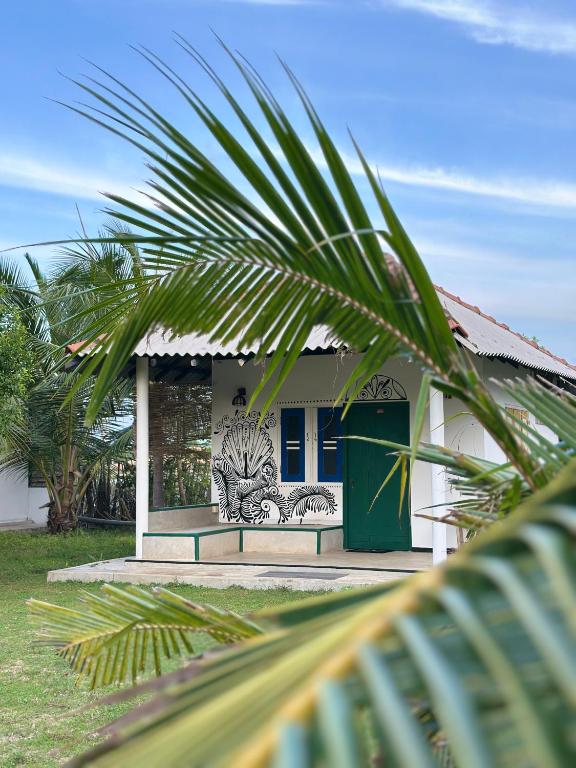 a house with a green door and a palm tree at PointBreak Resort in Kalpitiya