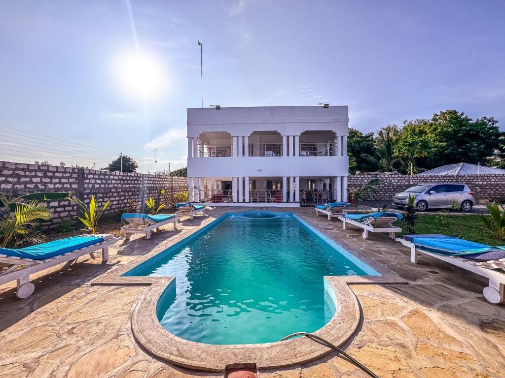 a villa with a swimming pool in front of a house at White House villa in Malindi