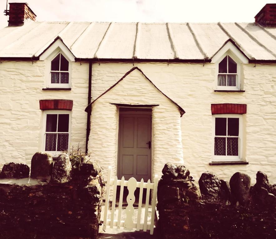 a white house with a white fence in front of it at Seaside Cottage in HAW