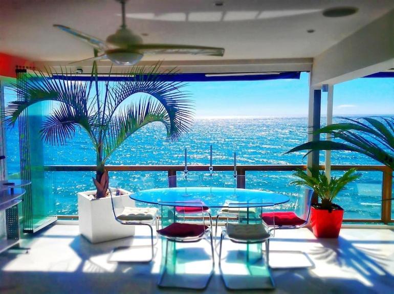 a table and chairs in a room with a view of the ocean at Malibu Beach Deluxe Wohnung Strandlage in Benalmádena