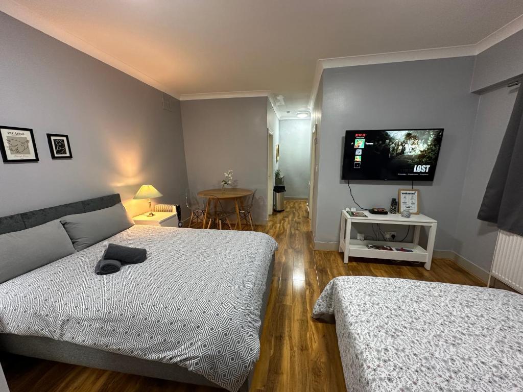 een slaapkamer met twee bedden en een flatscreen-tv bij CENTRAL Ground Floor Studio in Londen