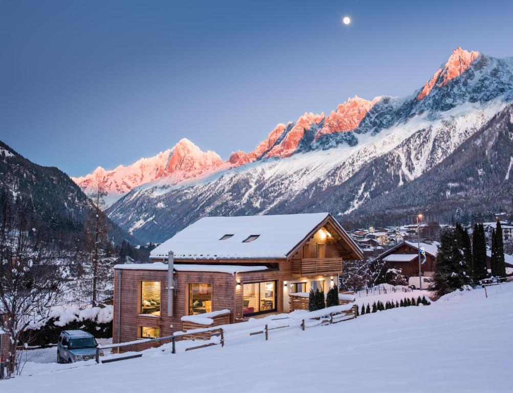 une maison dans la neige avec des montagnes en arrière-plan dans l'établissement Chalet Rubicon, aux Houches