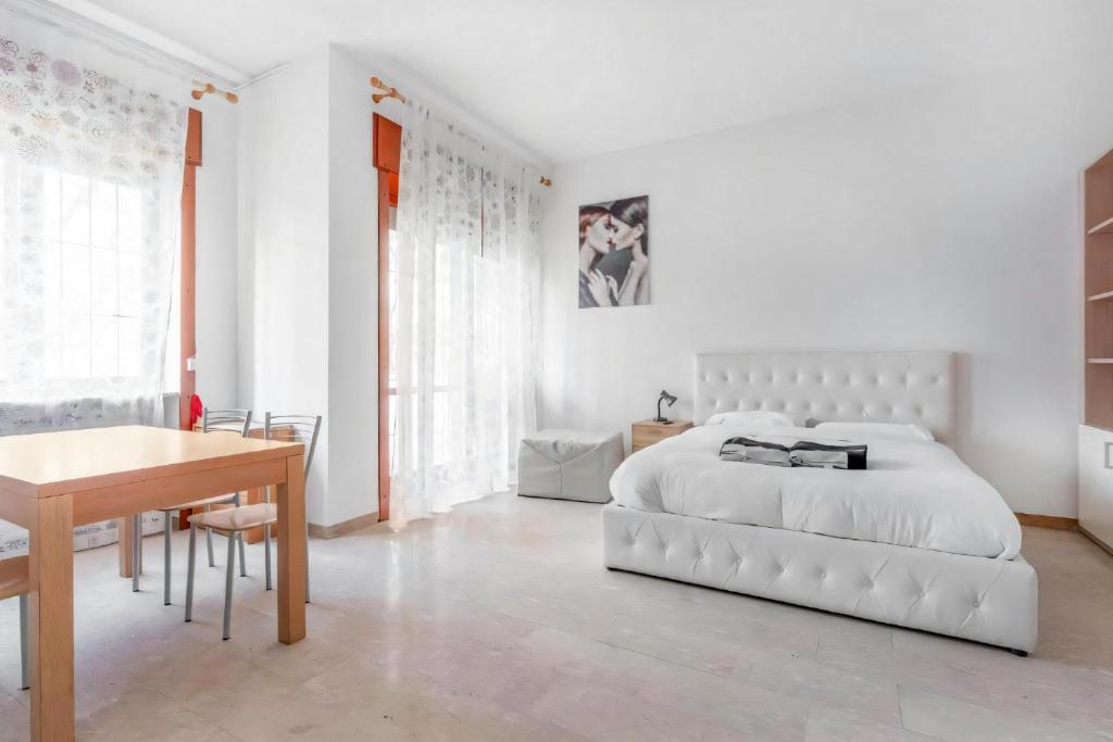 Un dormitorio blanco con una cama grande y un escritorio. en Moncler House Navigli, en Milán