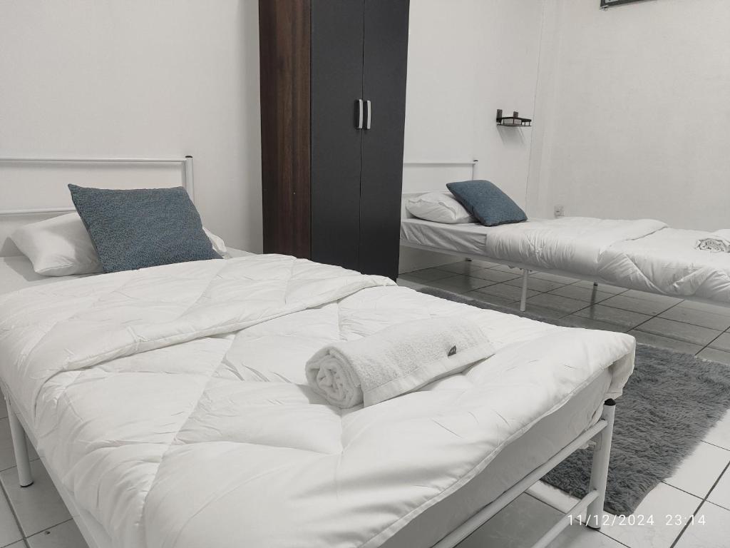 Un dormitorio con dos camas con sábanas blancas y almohadas azules. en TDT STAY-Homestay, en Keningau