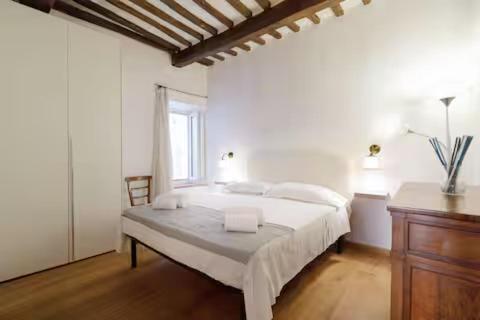 a white bedroom with a bed and a window at Appartamento nel Cuore del Centro Storico di Siena in Siena