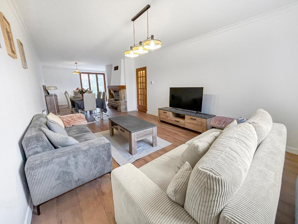 un salon avec deux canapés et une télévision à écran plat dans l'établissement Grande maison familiale au calme avec jardin partagé, à Eaubonne