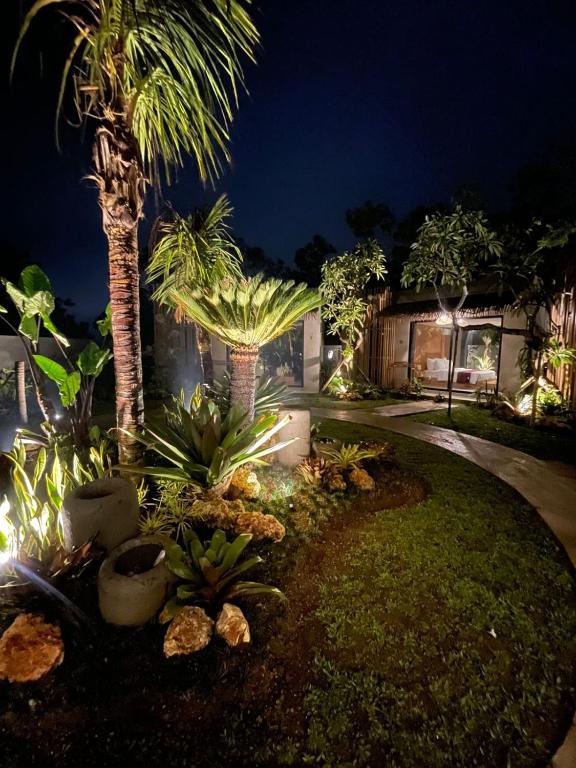 una casa con palmeras en un patio por la noche en Widji Garden Villa, en Uluwatu