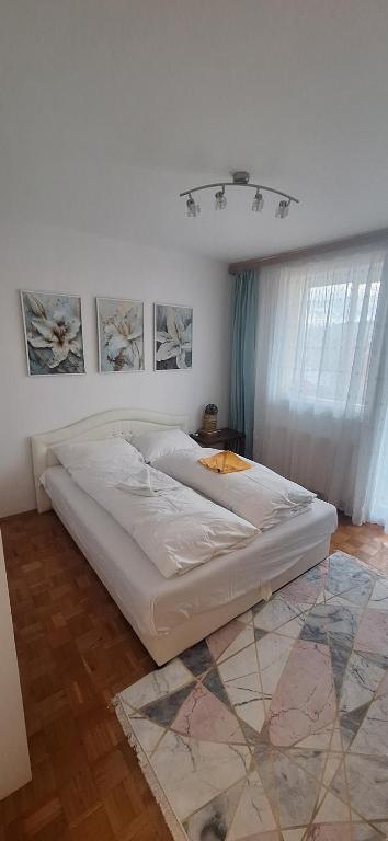 Una cama blanca en una habitación con ventana. en Apartman Sky, en Sarajevo
