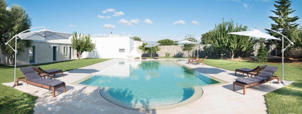 Una piscina en un patio con sillas y sombrillas. en Masseria Il Mandorlo Fiorito x 8 Piscina Privata, en Ceglie Messapica