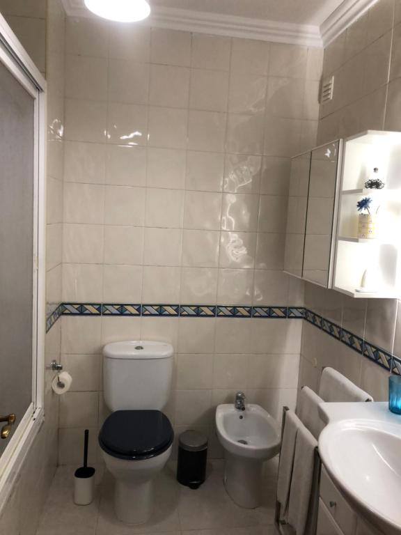 a white bathroom with a toilet and a sink at Casa das Conchas in Ericeira