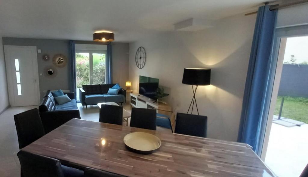 un salon avec une table et des chaises et un salon dans l'établissement Maison calme proche mer, à Ver-sur-Mer