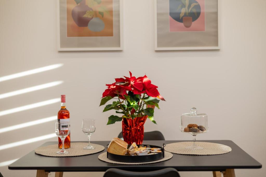 a table with two plates of food and a vase with red flowers at Celestia House in Kalabaka