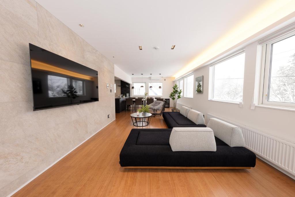ein Wohnzimmer mit einer Couch und einem Fernseher an der Wand in der Unterkunft Experience R, Rusutsu in Kimobetsu