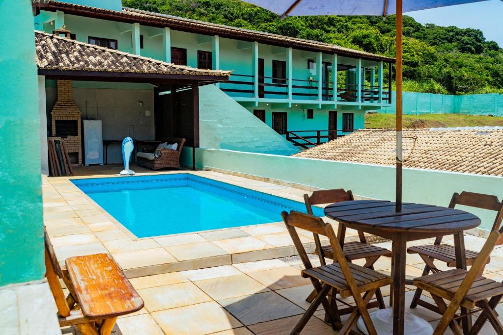 a table with an umbrella next to a swimming pool at Tucanos Buzios in Búzios