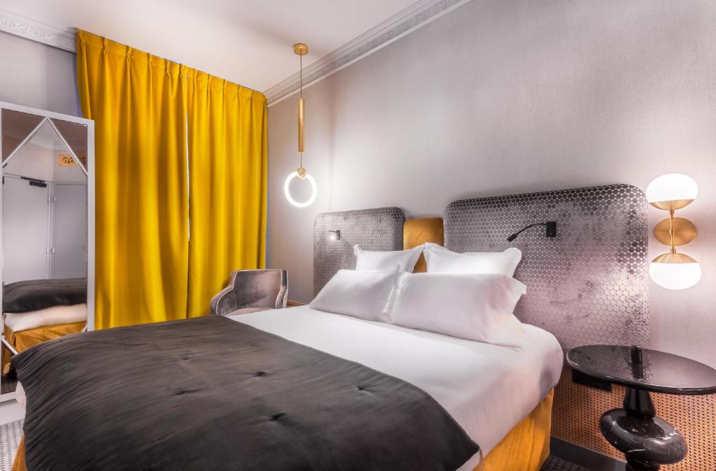 a hotel room with a bed and a yellow curtain at Handsome Hotel in Paris