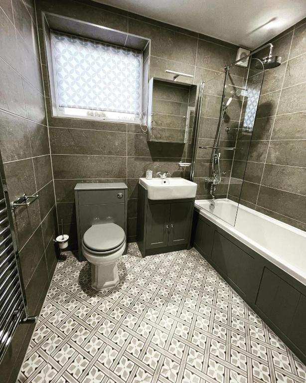 a bathroom with a toilet and a sink and a tub at Balincourt in Bournemouth