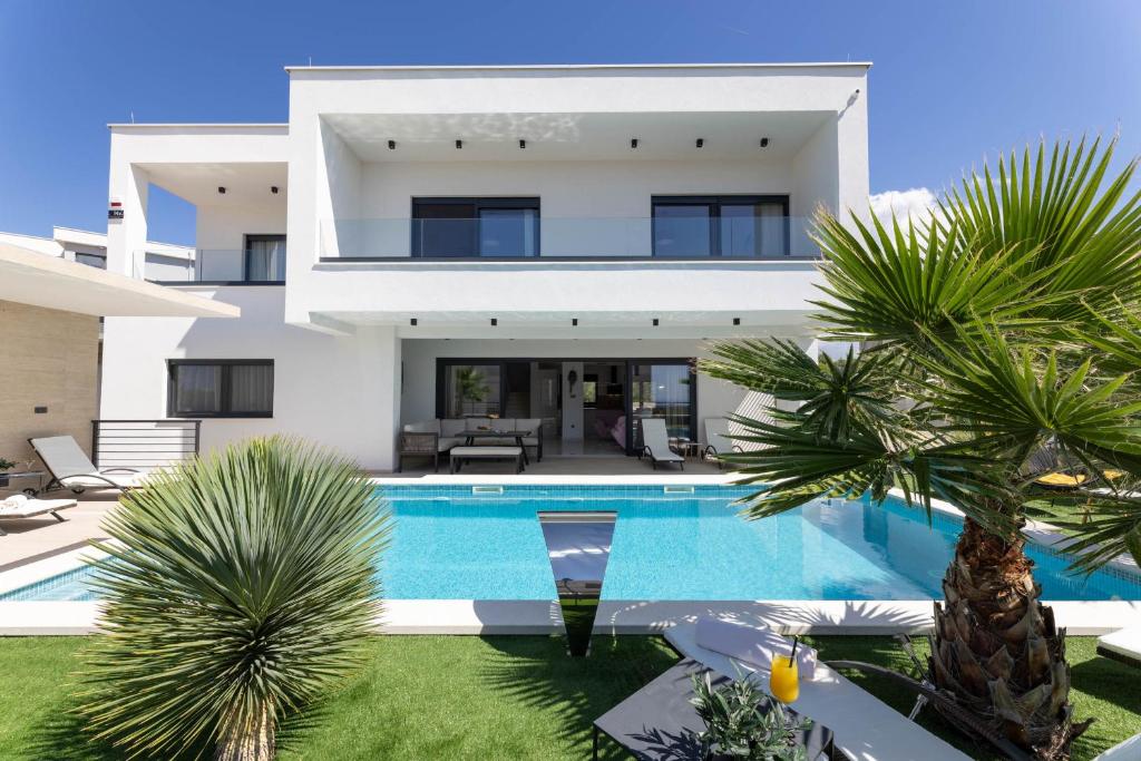 een groot wit huis met een zwembad en palmbomen bij Villa Golden Shine in Primošten