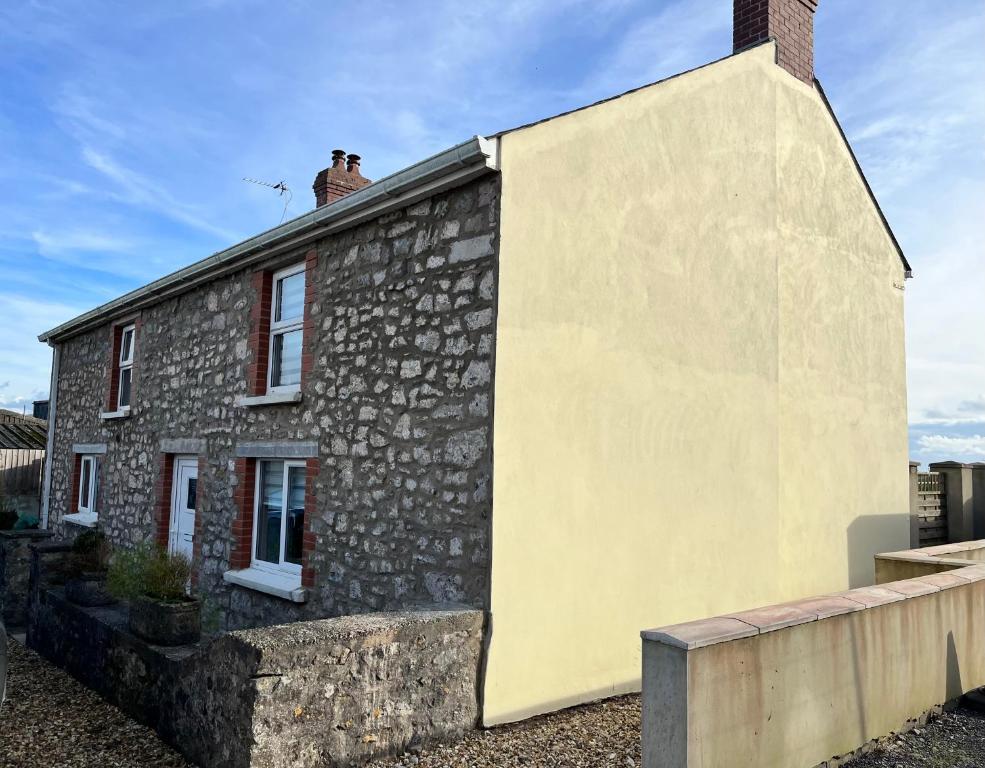 a stone house with a chimney on top of it at Homely Pembrokeshire Farmhouse in Tenby