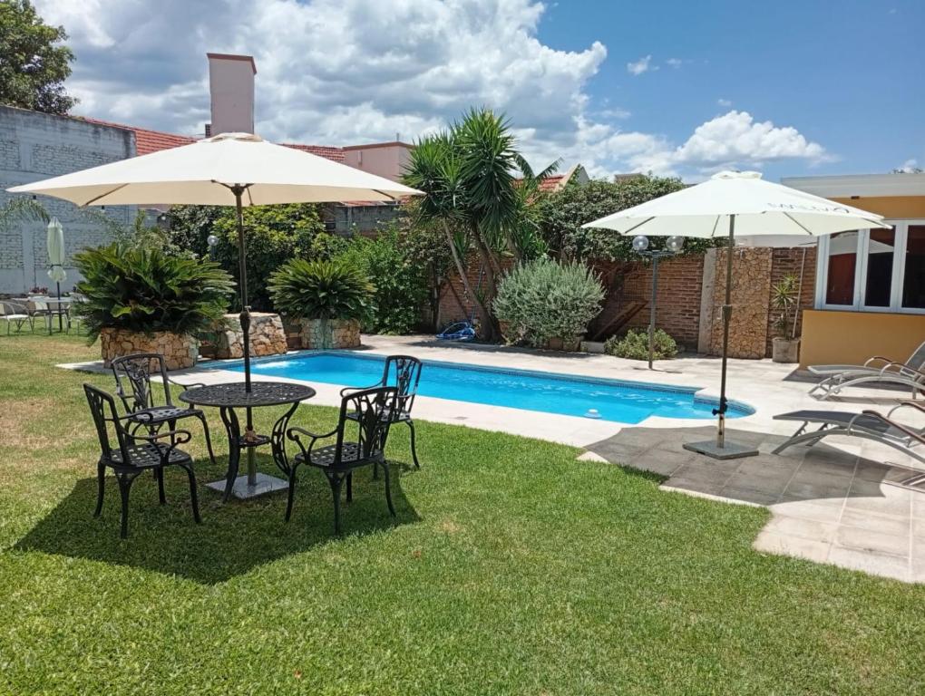 a table and chairs with umbrellas next to a pool at CASABLANCA CATAMARCA Guest House in San Fernando del Valle de Catamarca
