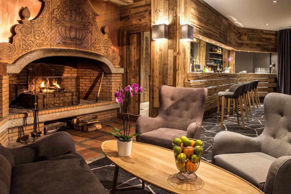 a lobby with a fireplace and a table and chairs at Le Pic Blanc in L'Alpe-d'Huez
